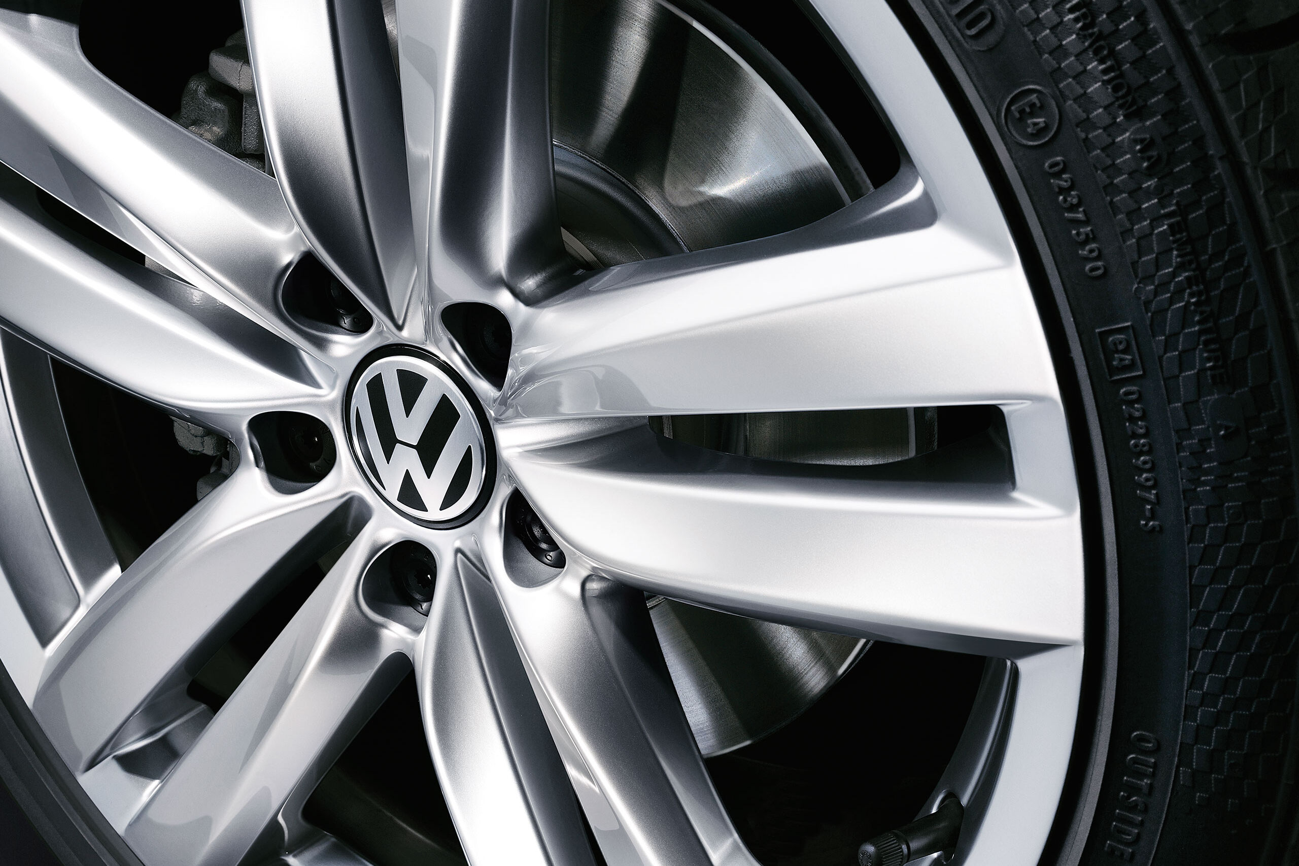 Uma vista detalhada de uma roda Volkswagen Golf VI com pneus de marca e jante VW