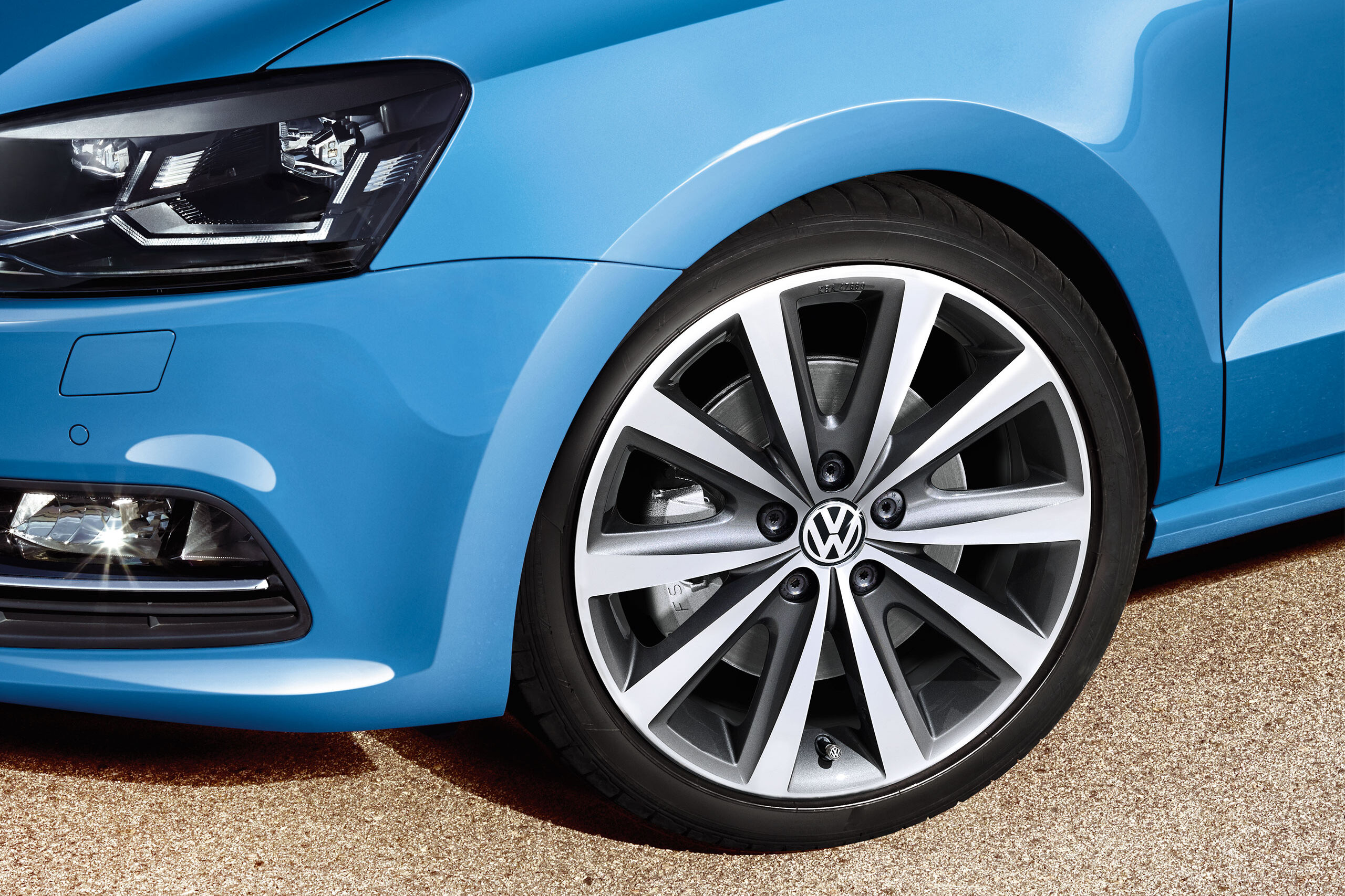 Uma vista detalhada de uma roda Polo 5 azul com pneu e jante VW Genuine - Acessórios Volkswagen