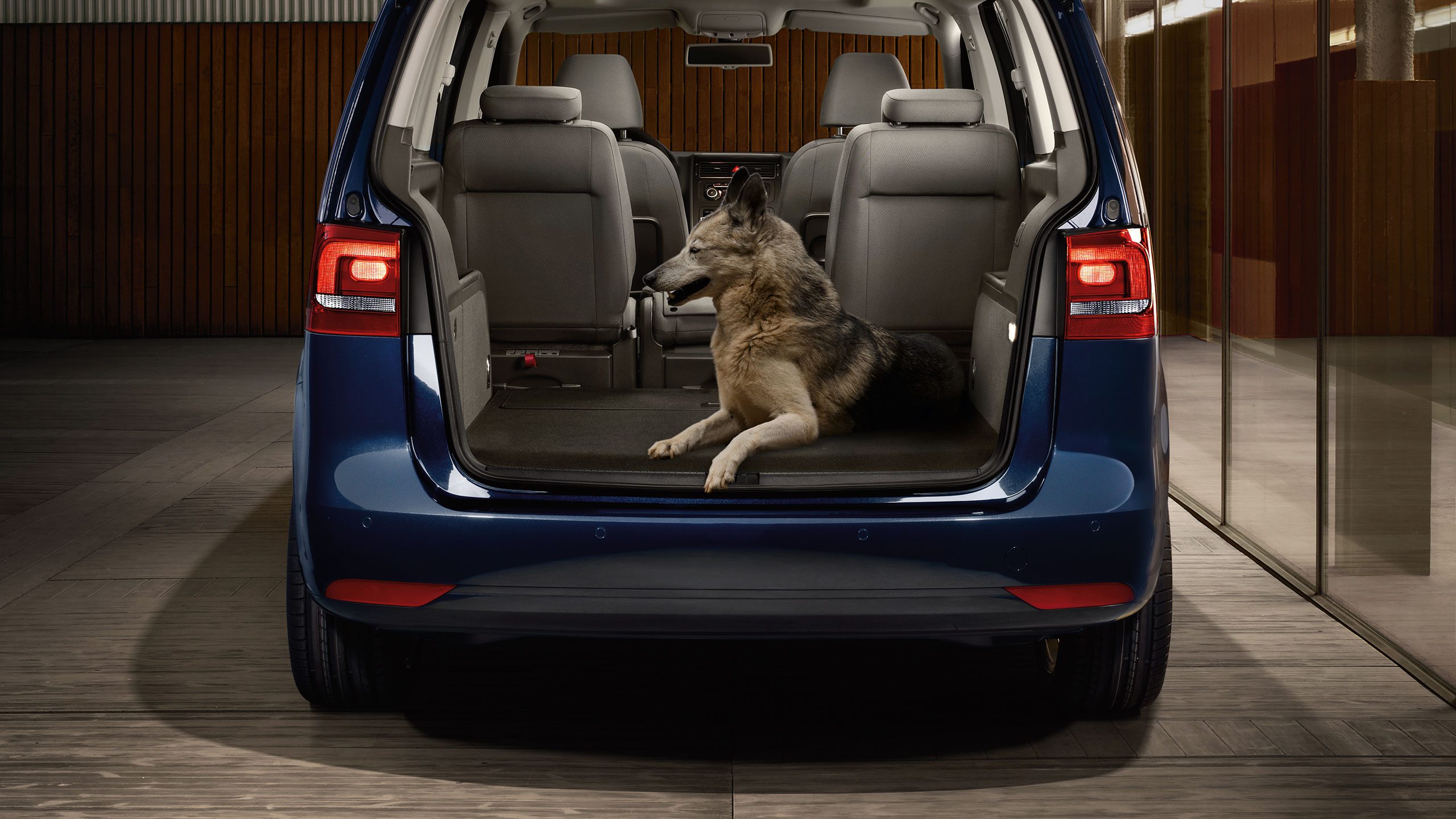 Um carro VW azul com uma bagageira aberta com um cão no interior