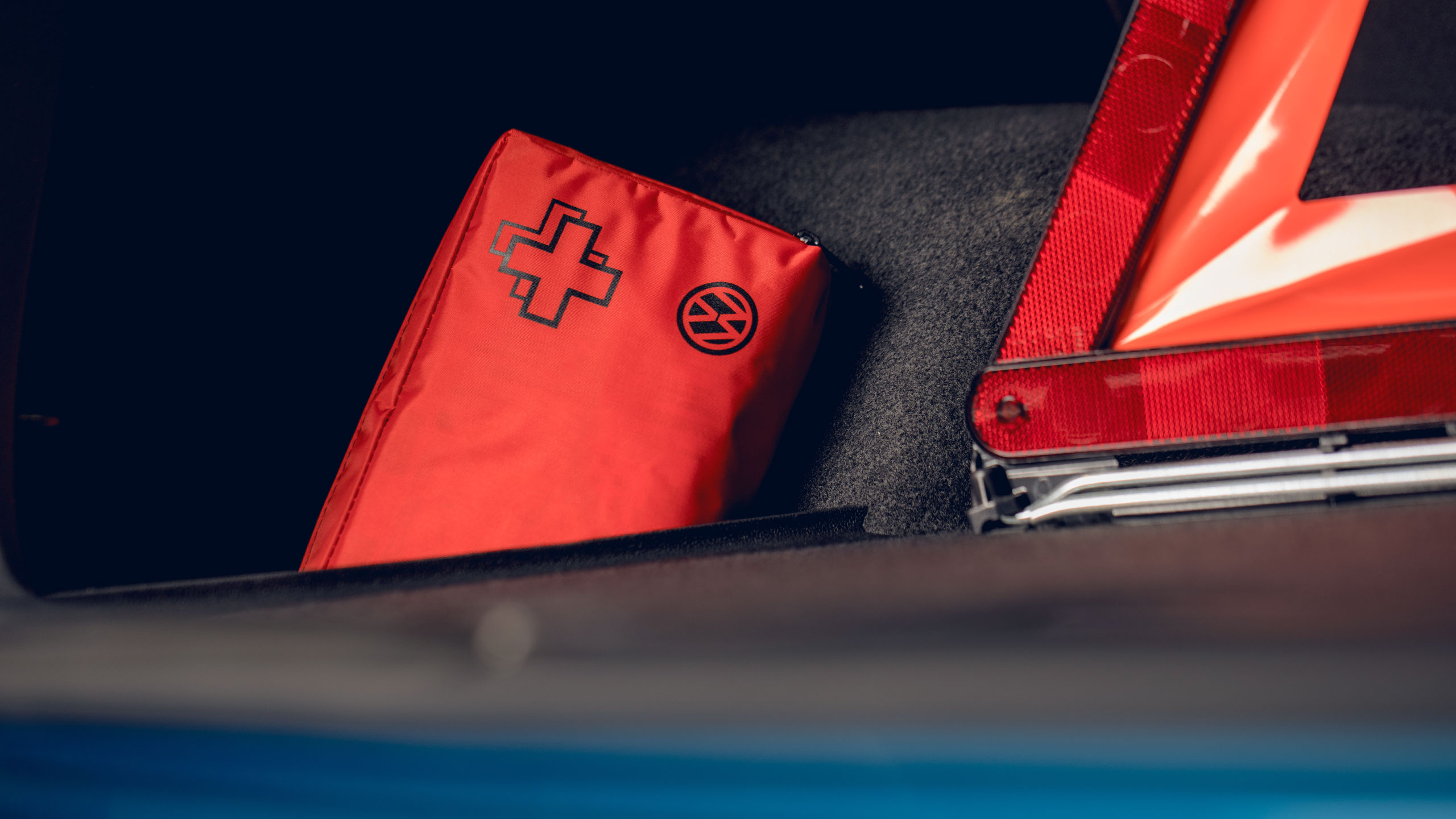 Um kit de primeiros-socorros e o triângulo de pré-sinalização da Volkswagen Acessórios na bagageira do carro.