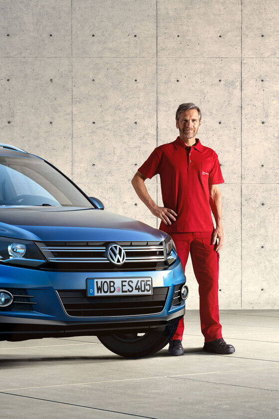 Um empregado do Serviço de Economy ao lado de um Volkswagen Tiguan azul