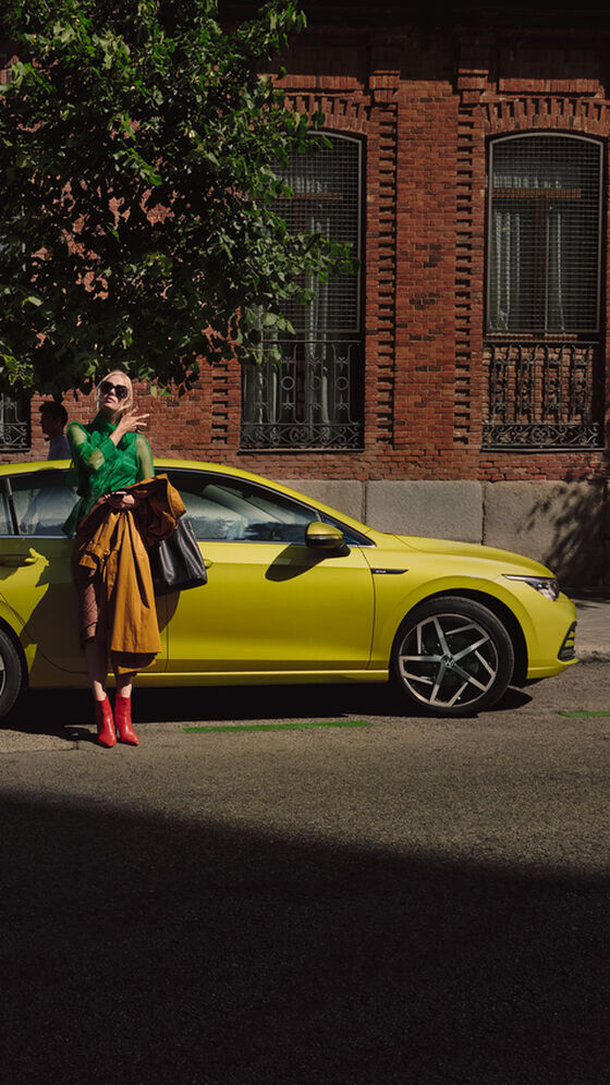 Um casal tira uma selfie junto de um VW Golf amarelo