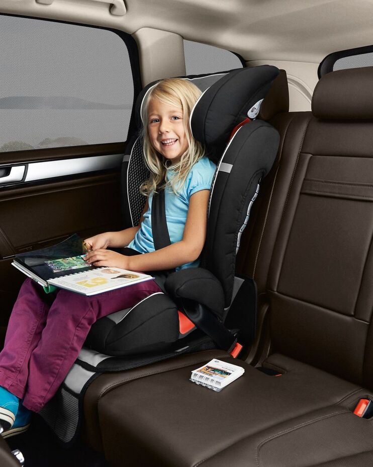Ein Mädchen sitzt in einem Kindersitz in einem VW