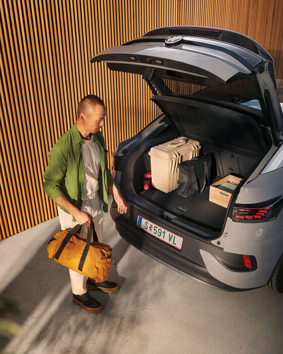 VW ID.5 com bagageira aberta e bagagem no interior, sob a tampa da bagageira aberta vê-se um homem de pasta na mão