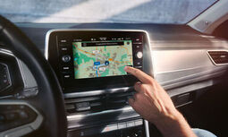 Interior do VW T-Roc, vista de pormenor do sistema Infotainment Discover Media, com uma mão a comandá-lo