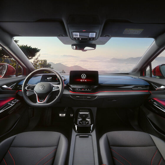 Habitáculo de um VW ID.5 GTX vermelho. Vista do volante, ecrã, bancos, molduras e espelho retrovisor.