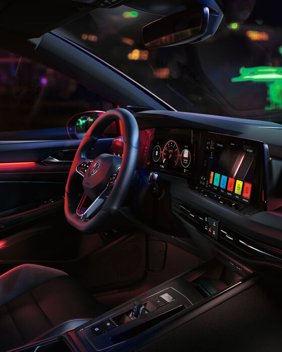 Interior do VW Golf GTI, cockpit com iluminação ambiente vermelha, com foco no banco do passageiro.