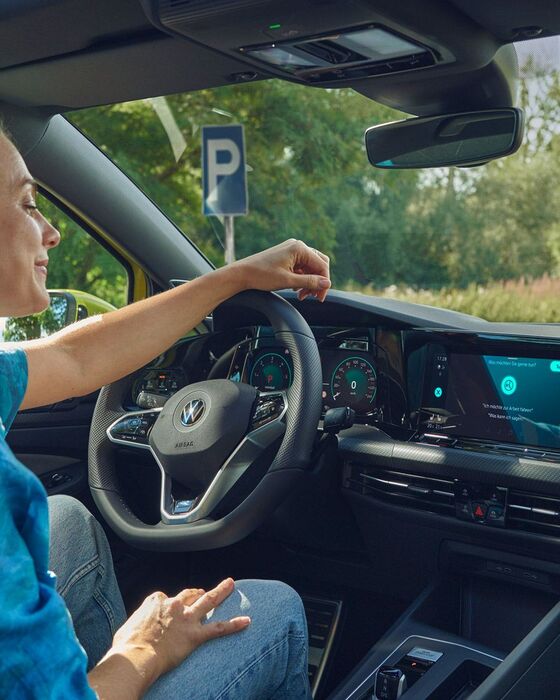 Uma mulher a usar o comando de voz no familiar VW Golf Variant