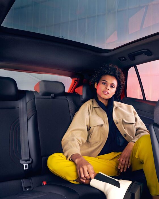 VW ID.4 GTX vista interior. Mulher sentada no banco de trás com a perna puxada para cima.