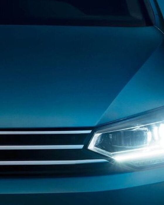 Frente do VW Touran ao anoitecer com faróis LED e luzes de circulação diurna ligadas.