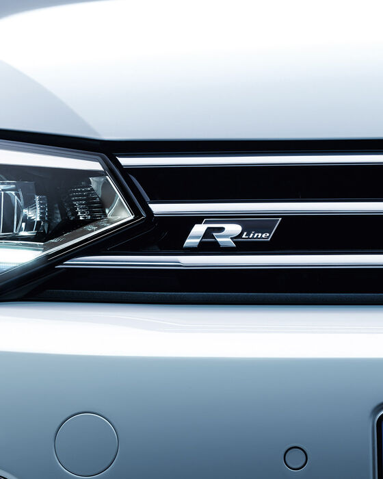 Pormenor da frente do VW Touran com faróis cortados e o logótipo "R-Line" na grelha do radiador