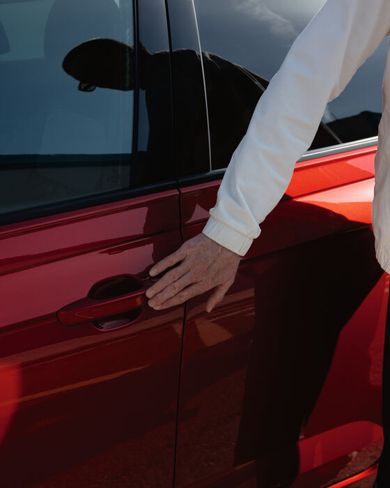 Homem agarra com a mão a maçaneta de um VW Taigo vermelho