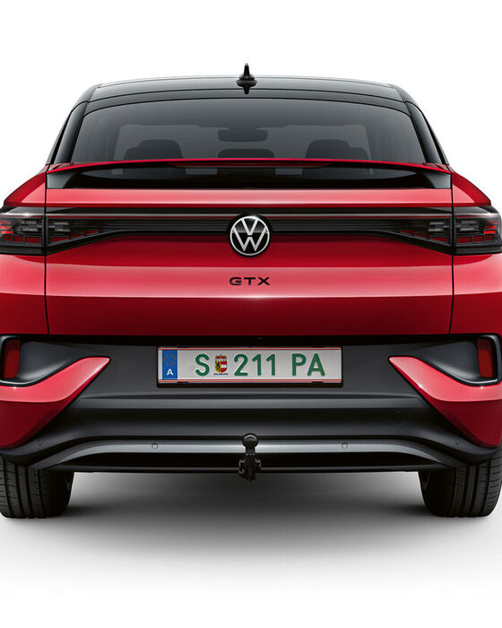Um VW ID.5 GTX vermelho desloca-se dinamicamente numa estrada, puxando um atrelado com uma mota de cross