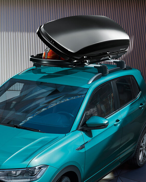 Um VW T-Roc turquesa com uma caixa de acessórios de tejadilho aberta.