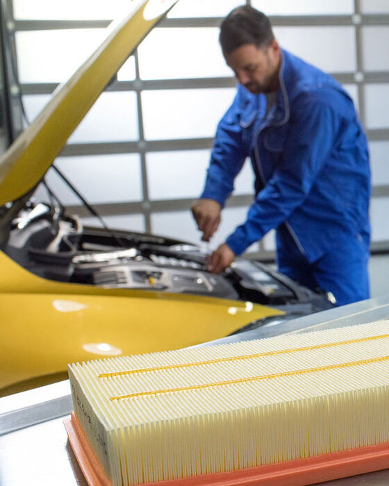 Um empregado de serviço da VW verifica o óleo enquanto a inspeção é feita num VW Golf amarelo