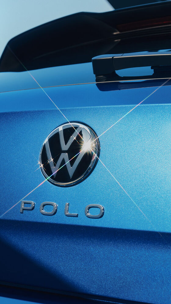 Vista de pormenor do emblema VW e da inscrição "Polo" na porta da bagageira de um Polo azul. 