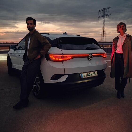 Vista traseira de um homem e uma mulher de pé em frente ao VW ID.4