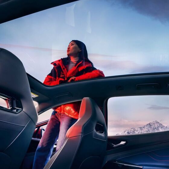 VW ID.4 GTX Vista interior através de teto panorâmico com uma mulher ao lado do SUV desportivo 100% elétrico.