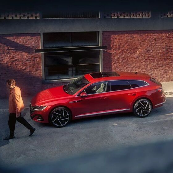 Homem passa em frente a um VW Arteon Shooting Brake vermelho estacionado