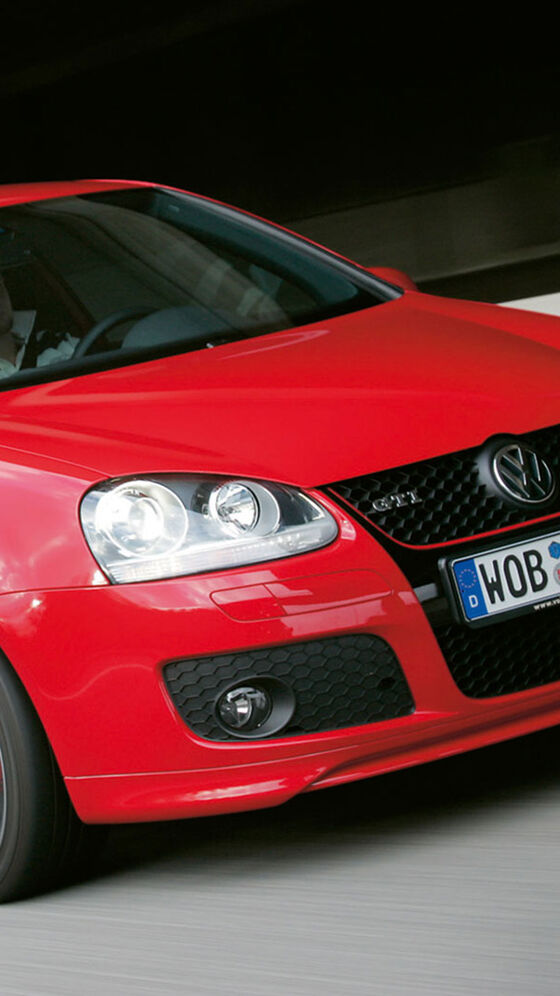 Um homem conduz num VW Golf V GTI vermelho
