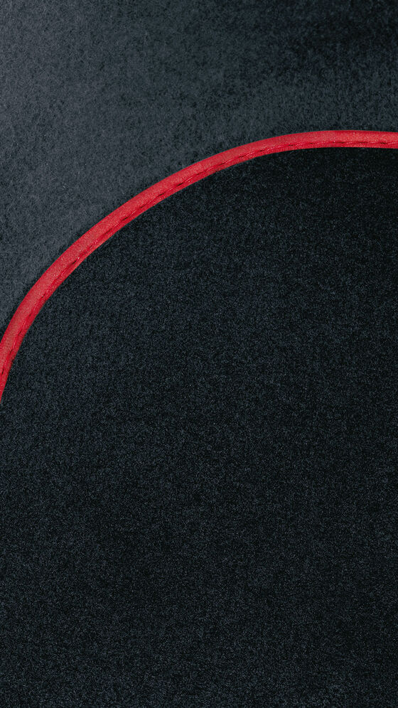Uma vista detalhada de um tapete de golfe preto V com detalhes vermelhos dos Acessórios VW