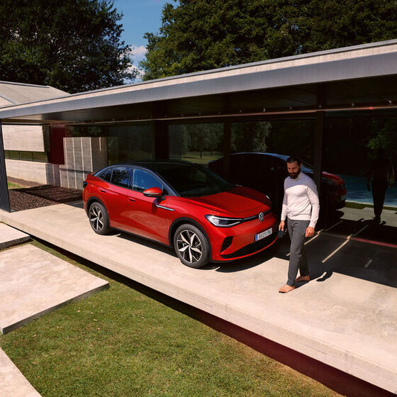 VW ID.5 GTX vermelho a estacionar em frente de uma casa. Um homem vai a passar.