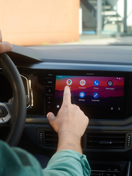 Vista do ecrã do VW Polo com funções We Upgrade. Homem sentado ao volante, a operar o ecrã. 