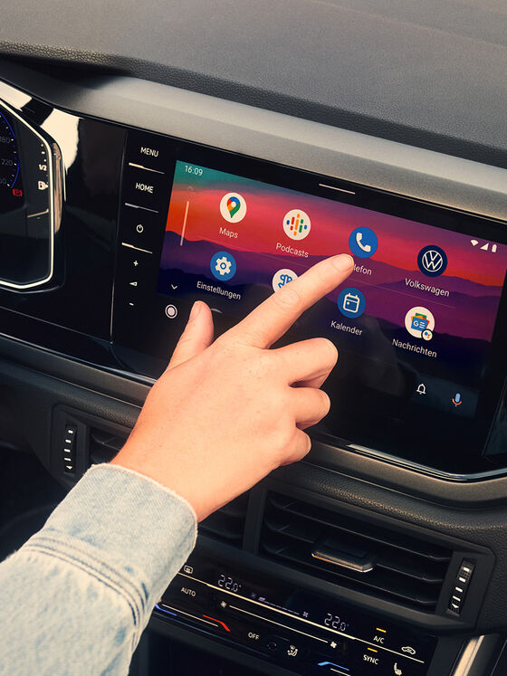 Ecrã do novo VW Polo aberto no Android Auto™ da Google. Uma mão opera o ecrã. 