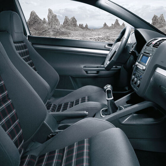 O interior de um VW Golf 5 com capas de assento xadrez e vários destaques técnicos e de conforto