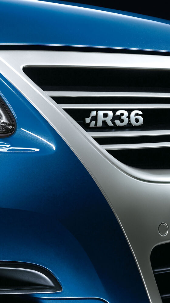 Vista detalhada de um carro VW Passat R36 azul com o emblema "R36" na grelha do radiador.