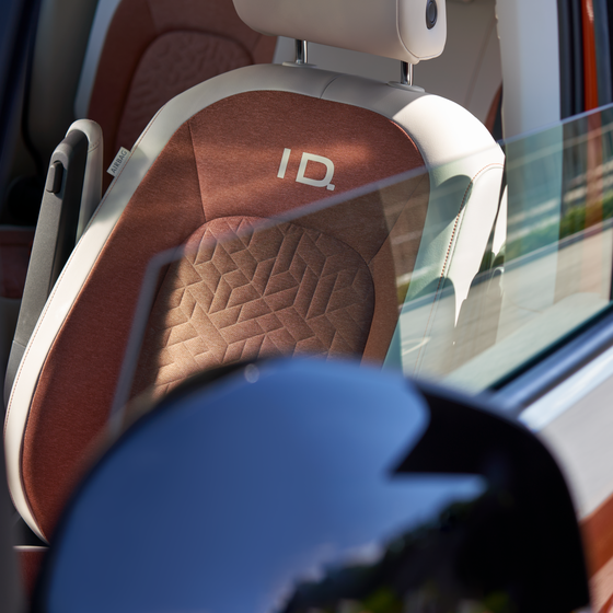 Uma rapariga e um rapaz sentados no banco de trás de um VW ID.Buzz estacionado